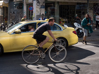 A man is passing in front of a Taxi riding bicycle near Monastiraki square in Athens, Greece on May 18, 2022. A committee of experts from th...