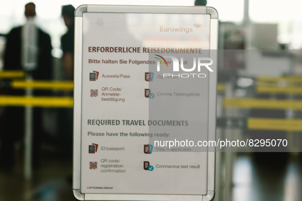 a sign of travel documents required is seen in front of Eurowings checkin counter at Cologne & Bonn airport on May 25, 2022 as Germany will...