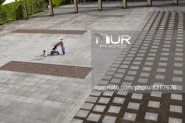 A toddler plays with his mother at a deserted plaza in Yokohama, Japan on 27 May. 