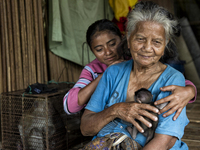 Minah Bt Raya(72) and Siti Bt Kassim(23) at their wooden house with her pet, a baby monkey. Malaysia is one of the most fast developing coun...