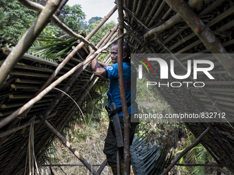 Tok Ulang(65) is building a top roof of new house.  Malaysia is one of the most fast developing country nevertheless , the modernism there i...