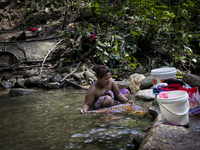 Mak Bakok(28) is washing clothes in the stream. As there is no supply of electronic , washing clothes in the stream is a party of thier usua...