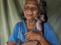 Minah Bt Raya(72) with her pet, a baby monkey.  Malaysia is one of the most fast developing country nevertheless , the modernism there is a...