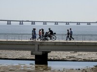 A group of people are seen performing outdoor activities in the surroundings of the Vasco da Gama walkway, close to the Tejo river. Lisbon,...