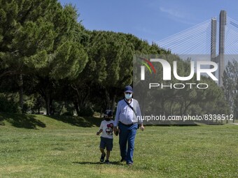 A man wearing protective mas is seen walking with a child near the  Vasco da Gama walkway, close to the Tejo river. Lisbon, 02 May 2022. A m...