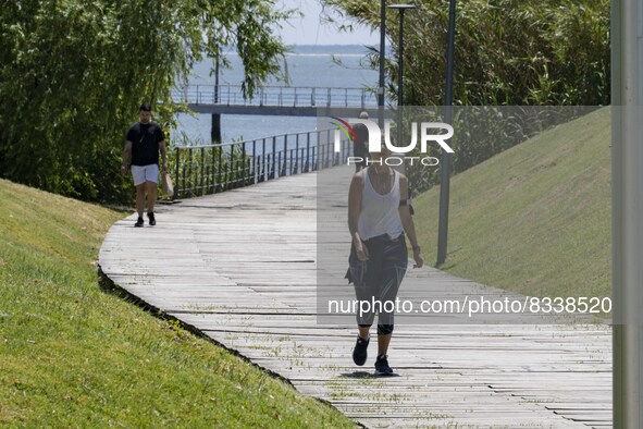 A group of people are seen performing outdoor activities in the surroundings of the Vasco da Gama walkway, close to the Tejo river. Lisbon,...