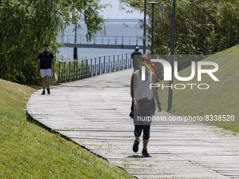 A group of people are seen performing outdoor activities in the surroundings of the Vasco da Gama walkway, close to the Tejo river. Lisbon,...