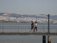 A group of people are seen performing outdoor activities in the surroundings of the Vasco da Gama walkway, close to the Tejo river. Lisbon,...