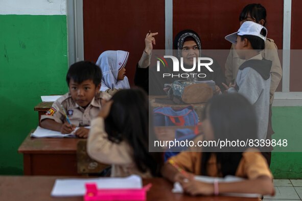 A teacher is seen teaching students at a school in Tugu Utara Village, Regency Bogor, West Java province, Indonesia on 2 June, 2022. 