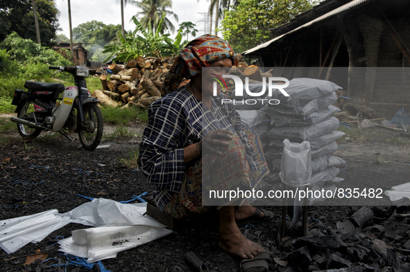 Female worker is packing the charcoal. Kampung Keluat, Kelantan / Malaysia. *360 hours of waiting. 50 Cent's happy. Charcoal needs 360 hours...