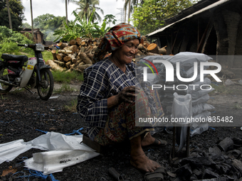 Female worker is packing the charcoal. Kampung Keluat, Kelantan / Malaysia. *360 hours of waiting. 50 Cent's happy. Charcoal needs 360 hours...