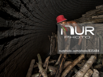 Male worker is stacked up many Oaks high in the charcoal dome / Kampung Keluat, Kelantan / Malaysia. *360 hours of waiting. 50 Cent's happy....