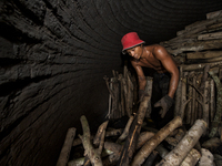 Male worker is stacked up many Oaks high in the charcoal dome / Kampung Keluat, Kelantan / Malaysia. *360 hours of waiting. 50 Cent's happy....