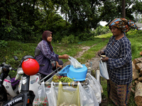 Female worker is buying some food from a small mobile shop. There is no market near to their village / Kampung Keluat, Kelantan / Malaysia....