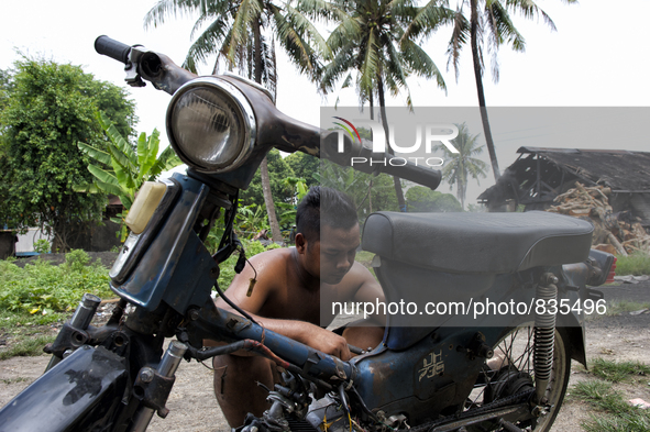 Male worker is repairing his a motorbike / Kampung Keluat, Kelantan / © Chris Jung
 