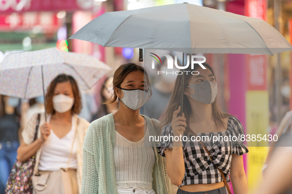 Hong Kong, China, 11 Jun 2022, Two young ladies walk under an umbrella in Sai Yeung Choi South Street in Mongkok. 