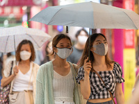 Hong Kong, China, 11 Jun 2022, Two young ladies walk under an umbrella in Sai Yeung Choi South Street in Mongkok. (