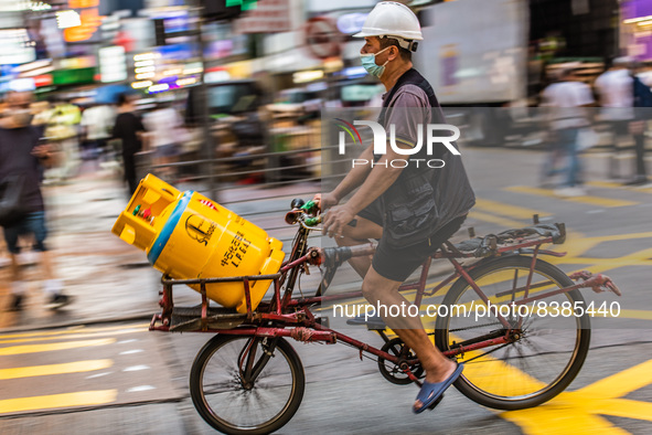 Hong Kong, China, 11 Jun 2022, A delivery man carries bottles of LPG gas on his bicycle in Mongkok. 