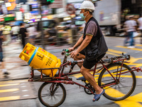 Hong Kong, China, 11 Jun 2022, A delivery man carries bottles of LPG gas on his bicycle in Mongkok. (