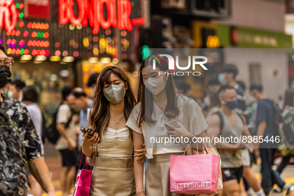 Hong Kong, China, 11 Jun 2022, Two young ladies cross a street in Mongkok after shopping in the area. 