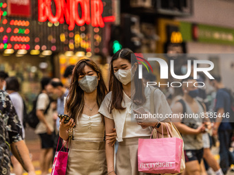 Hong Kong, China, 11 Jun 2022, Two young ladies cross a street in Mongkok after shopping in the area. (