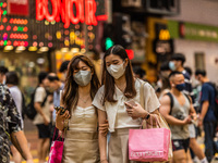 Hong Kong, China, 11 Jun 2022, Two young ladies cross a street in Mongkok after shopping in the area. (