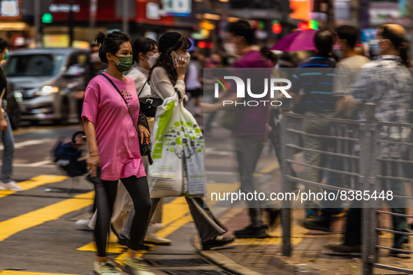 Hong Kong, China, 11 Jun 2022, People cross a street in Mongkok in this panned shot. 