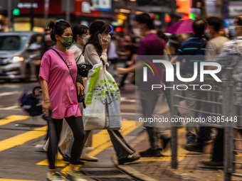 Hong Kong, China, 11 Jun 2022, People cross a street in Mongkok in this panned shot. (