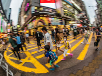 Hong Kong, China, 11 Jun 2022, A masked family crosses a street in Mongkok on a rainy day. (