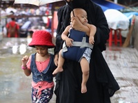 A woman walks thorugh a light rain with her children in Dhaka, Bangladesh on June 17, 2022. (