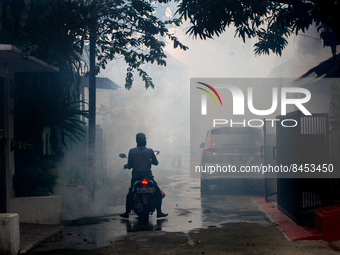 A motorist stops while a health workers fumigate a residential area to prevent mosquito breeding in Bogor, West Java, Indonesia on June 26,...