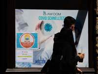 a couple walks pass a coronavirus test center in Cologne, Germany on July 1, 2022 as most people Germany will have to pay for covid test fro...