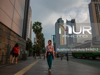 A woman wear protective face masks while walking at pedestrian in Jakarta on 5 July 2022. The Indonesian government on Tuesday, July 5, rais...