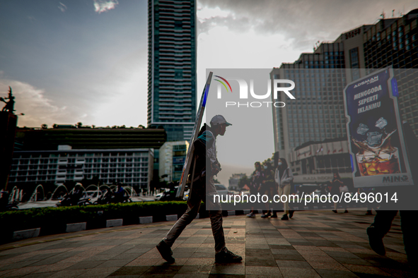 A man carries a walking billboard while walking at pedestrian in Jakarta on 5 July 2022. The Indonesian government on Tuesday, July 5, raise...