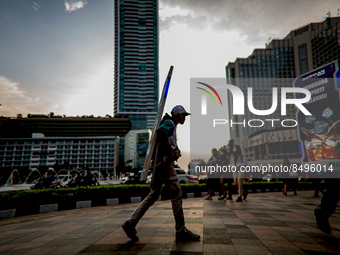 A man carries a walking billboard while walking at pedestrian in Jakarta on 5 July 2022. The Indonesian government on Tuesday, July 5, raise...