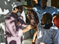 A health worker applies a Booster Dose of the Pfizer vaccine during vaccination campaign outside of the cattle market at Daulatkhan, Bhola,...