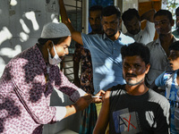 A health worker applies a Booster Dose of the Pfizer vaccine during vaccination campaign outside of the cattle market at Daulatkhan, Bhola,...