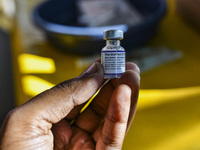 A health person hold a dose of Pfizer COVID-19 vaccine are seen during a vaccination campaign outside of the cattle market at Daulatkhan, Bh...