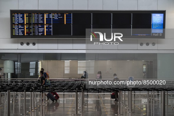 Travellers walk pass a flight arrival display board inside Hong Kong International Airport on July 7, 2022 in Hong Kong, China. The Hong Kon...