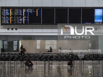 Travellers walk pass a flight arrival display board inside Hong Kong International Airport on July 7, 2022 in Hong Kong, China. The Hong Kon...