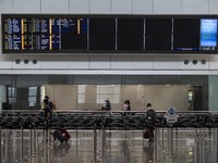 Travellers walk pass a flight arrival display board inside Hong Kong International Airport on July 7, 2022 in Hong Kong, China. The Hong Kon...