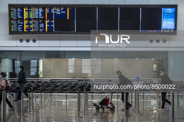 Travellers walk pass a flight arrival display board inside Hong Kong International Airport on July 7, 2022 in Hong Kong, China. The Hong Kon...