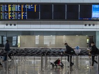 Travellers walk pass a flight arrival display board inside Hong Kong International Airport on July 7, 2022 in Hong Kong, China. The Hong Kon...