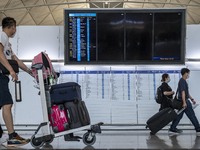 Travellers walk pass an electronic flight display board inside Hong Kong International Airport on July 7, 2022 in Hong Kong, China. The Hong...