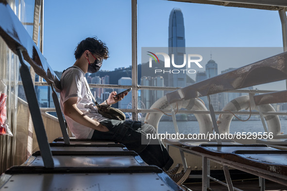 A Man looking at his phone while riding on the Star Ferry in front of the Hong Kong Skyline on July 12, 2022 in Hong Kong, China. The Hong K...