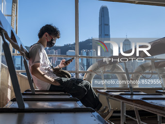 A Man looking at his phone while riding on the Star Ferry in front of the Hong Kong Skyline on July 12, 2022 in Hong Kong, China. The Hong K...