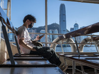 A Man looking at his phone while riding on the Star Ferry in front of the Hong Kong Skyline on July 12, 2022 in Hong Kong, China. The Hong K...