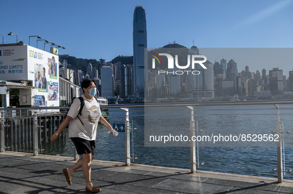 A women wearing a face mask walking pass the Hong Kong Skyline on July 12, 2022 in Hong Kong, China. The Hong Kong Government announce that...