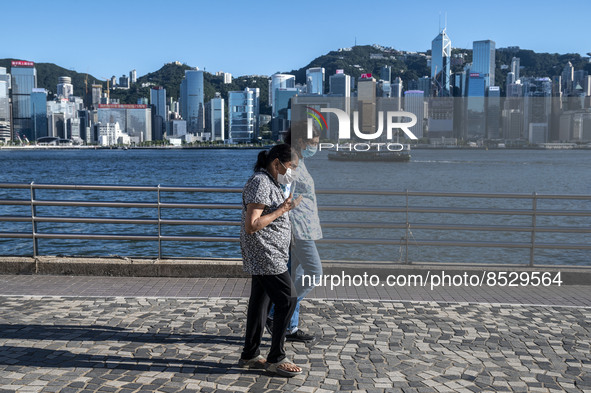 People wearing face masks walk pass the Hong Kong Skyline on July 12, 2022 in Hong Kong, China. The Hong Kong Government announce that it wo...