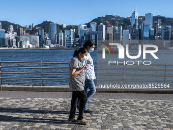 People wearing face masks walk pass the Hong Kong Skyline on July 12, 2022 in Hong Kong, China. The Hong Kong Government announce that it wo...